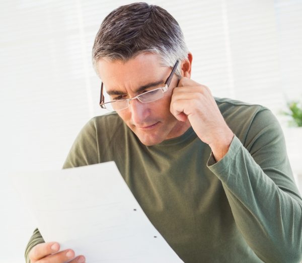 Image of man wearing glasses reading personal customer correspondence documents.