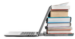 side view of open laptop leaned up against a stack of textbooks.