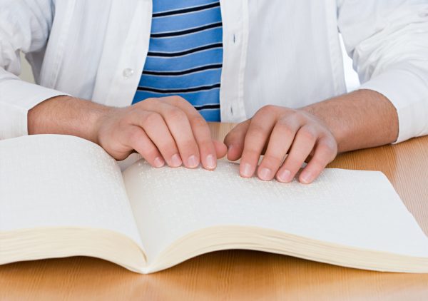 Image of a student reading braille textbooks