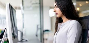 Side profile of a woman sitting at a desktop computer