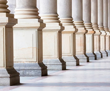 Image of pillars cascading along a long corridor, depicting a government building.