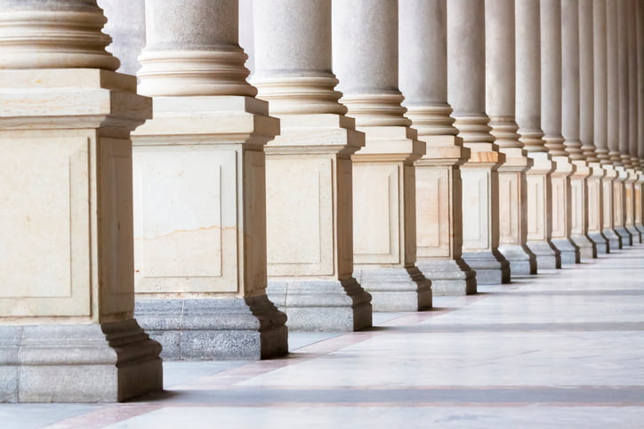 Image of pillars cascading along a long corridor, depicting a government building.