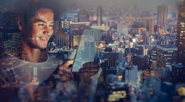 Image of a man on a mobile device (tablet), cityscape behind him