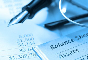 Image of eye glasses and pen resting on monthly financial statements.