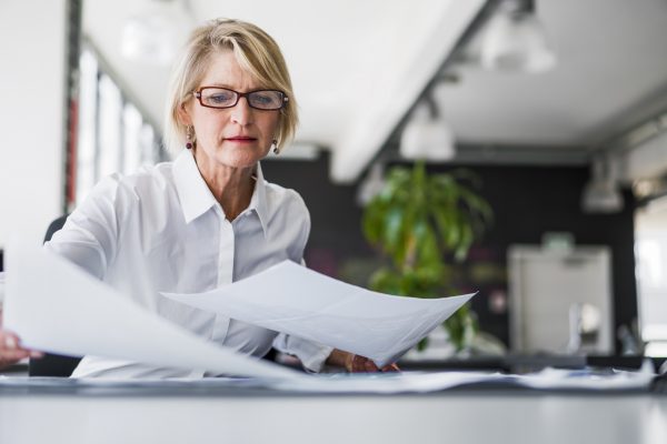 Image of a woman with glasses sorting through accessible documents on a table