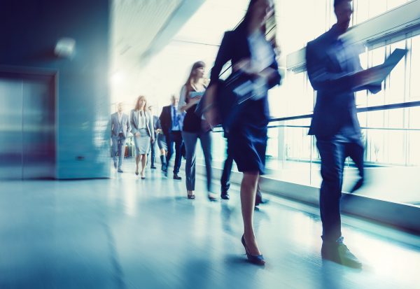 Image of people walking quickly along an office corridor depicting speed of high-quality accessible communications.